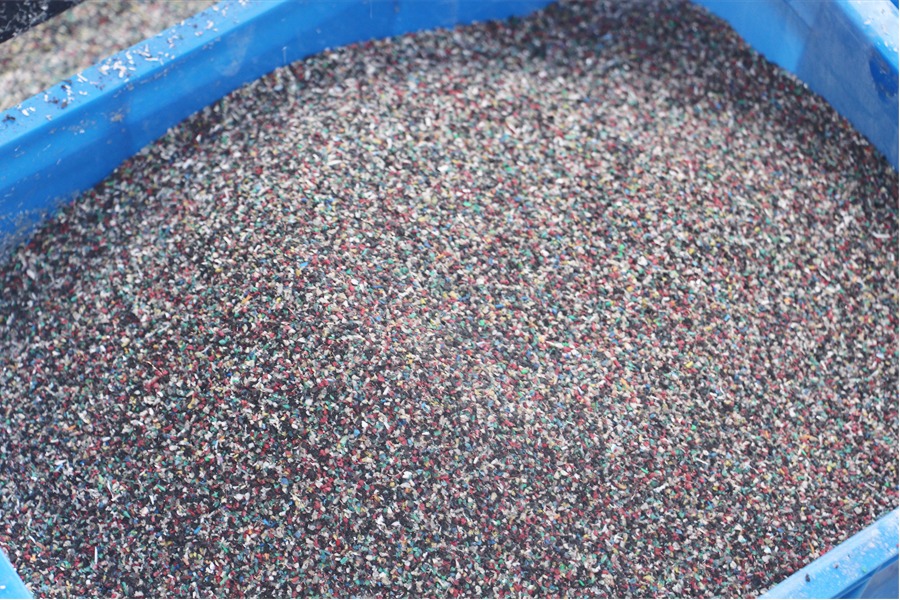 Recycled plastic granules separated from scrap wires stored in a storage bin.
