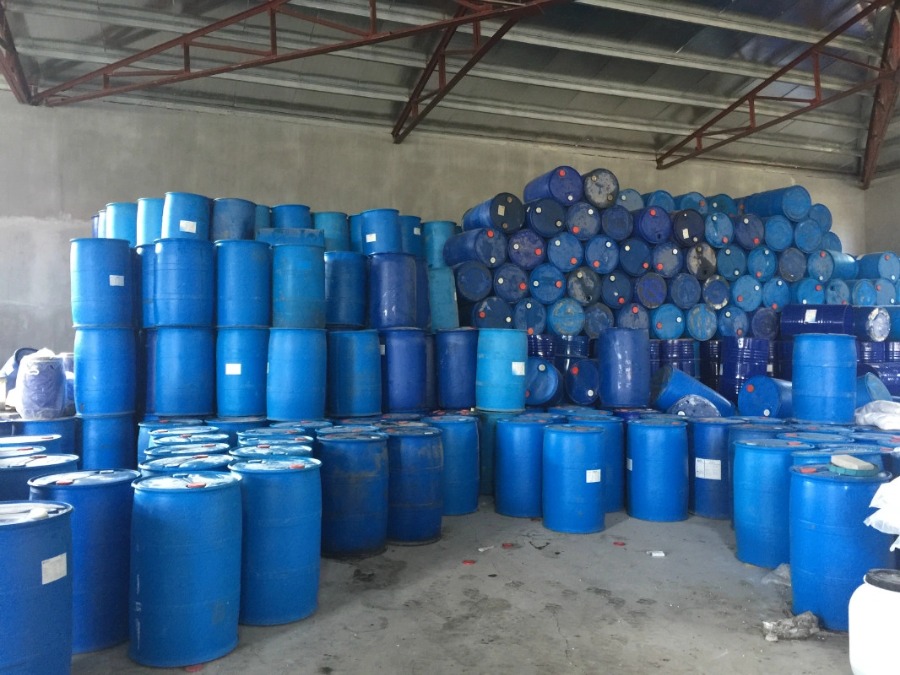 Stacked industrial blue plastic chemical drums waiting for shredding recycling
