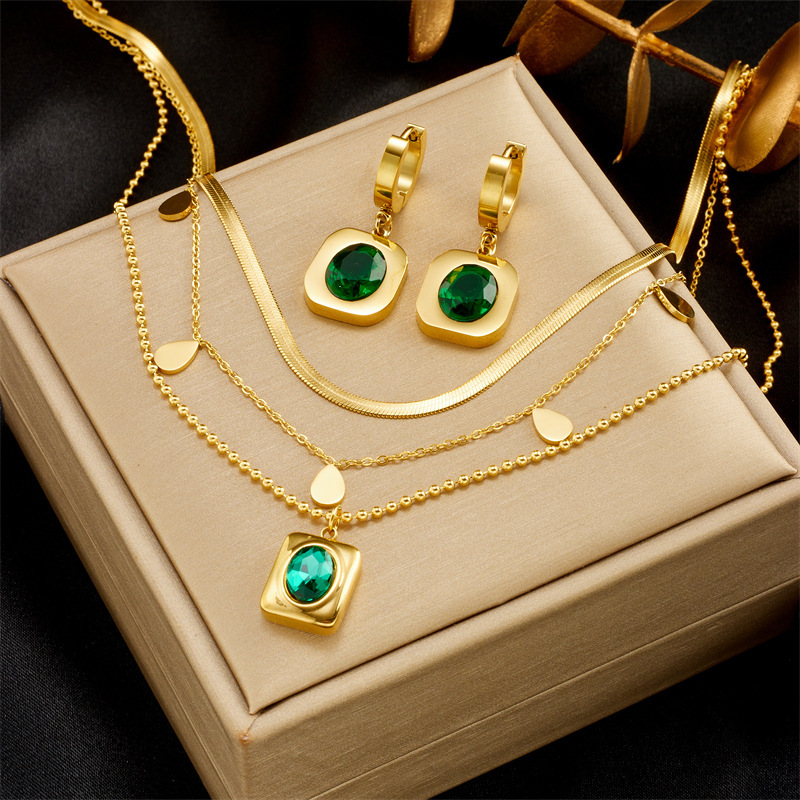 Niche luxury retro design titanium steel emerald zircon earrings and necklace set for elegant women.