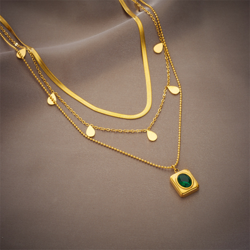Niche luxury retro design titanium steel emerald zircon earrings and necklace set for elegant women.