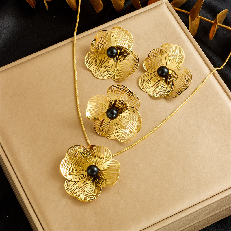 Stylish and elegant pearl necklace, earrings, and ring set featuring openwork petals and a pearl design.