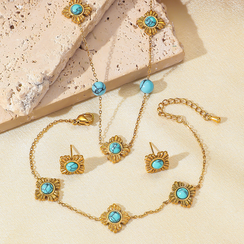 A trendy, modern Chinese-style three-piece stainless steel necklace, earrings, and bracelet set featuring four-petal flower inlay and turquoise.