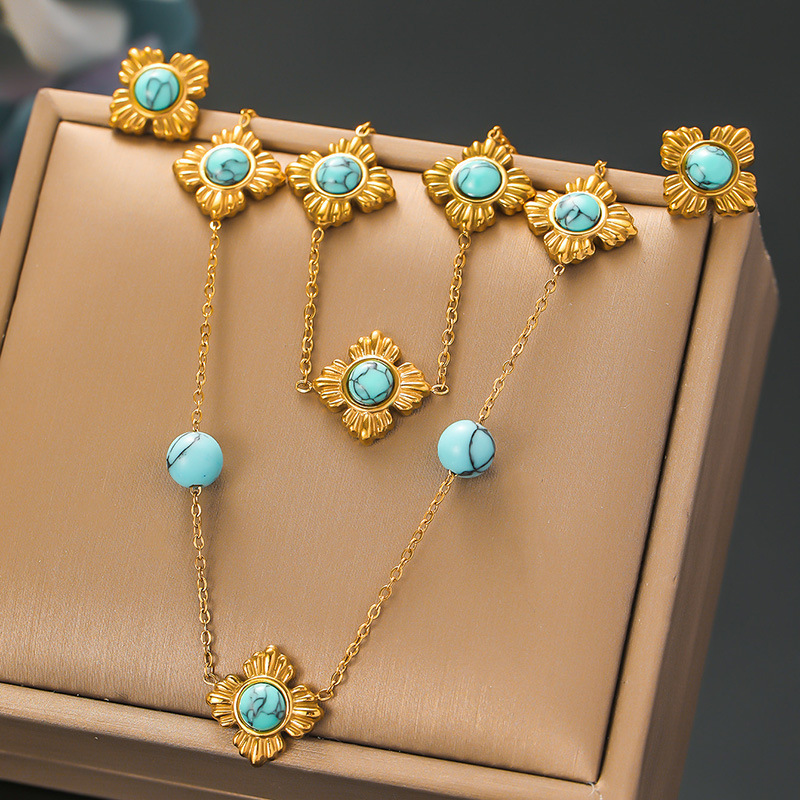 A trendy, modern Chinese-style three-piece stainless steel necklace, earrings, and bracelet set featuring four-petal flower inlay and turquoise.
