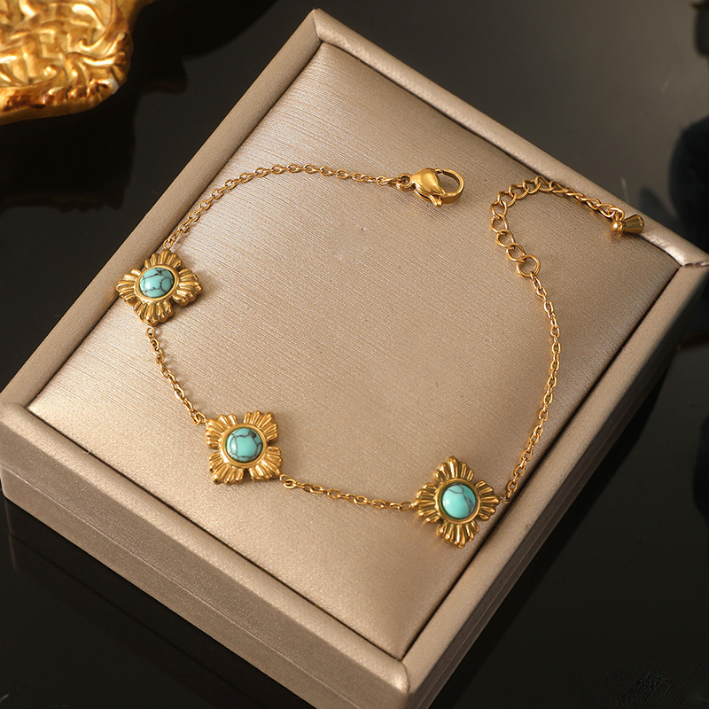 A trendy, modern Chinese-style three-piece stainless steel necklace, earrings, and bracelet set featuring four-petal flower inlay and turquoise.