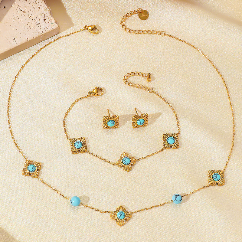 A trendy, modern Chinese-style three-piece stainless steel necklace, earrings, and bracelet set featuring four-petal flower inlay and turquoise.