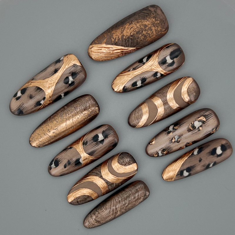 Close up of Law of the Wild oval nail highlighting hand-painted cheetah spots, gold foil details, and high-shine gloss