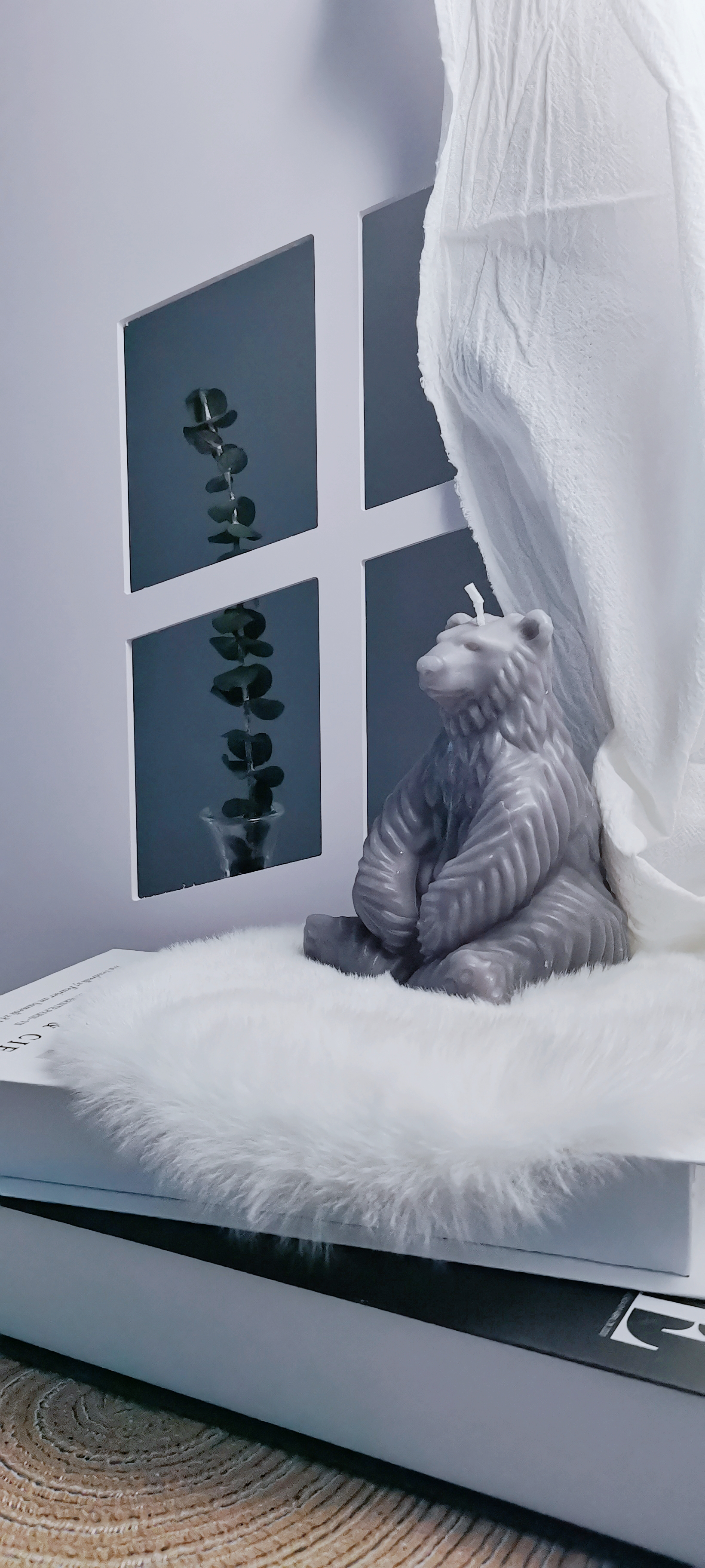 Gray Polar Bear Candle sitting on books by the window_vertical
