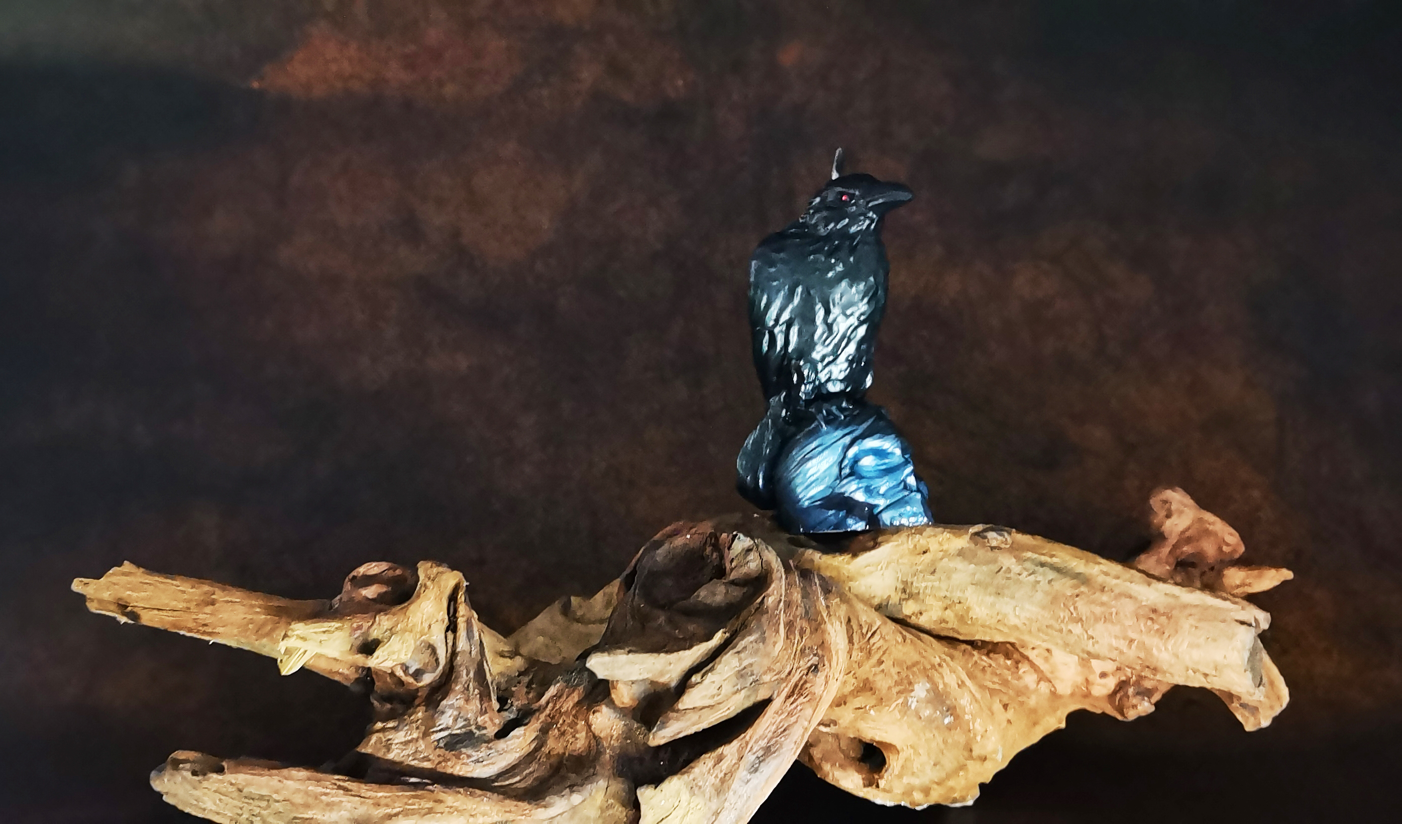 on a dead log standing a crow and skull candle