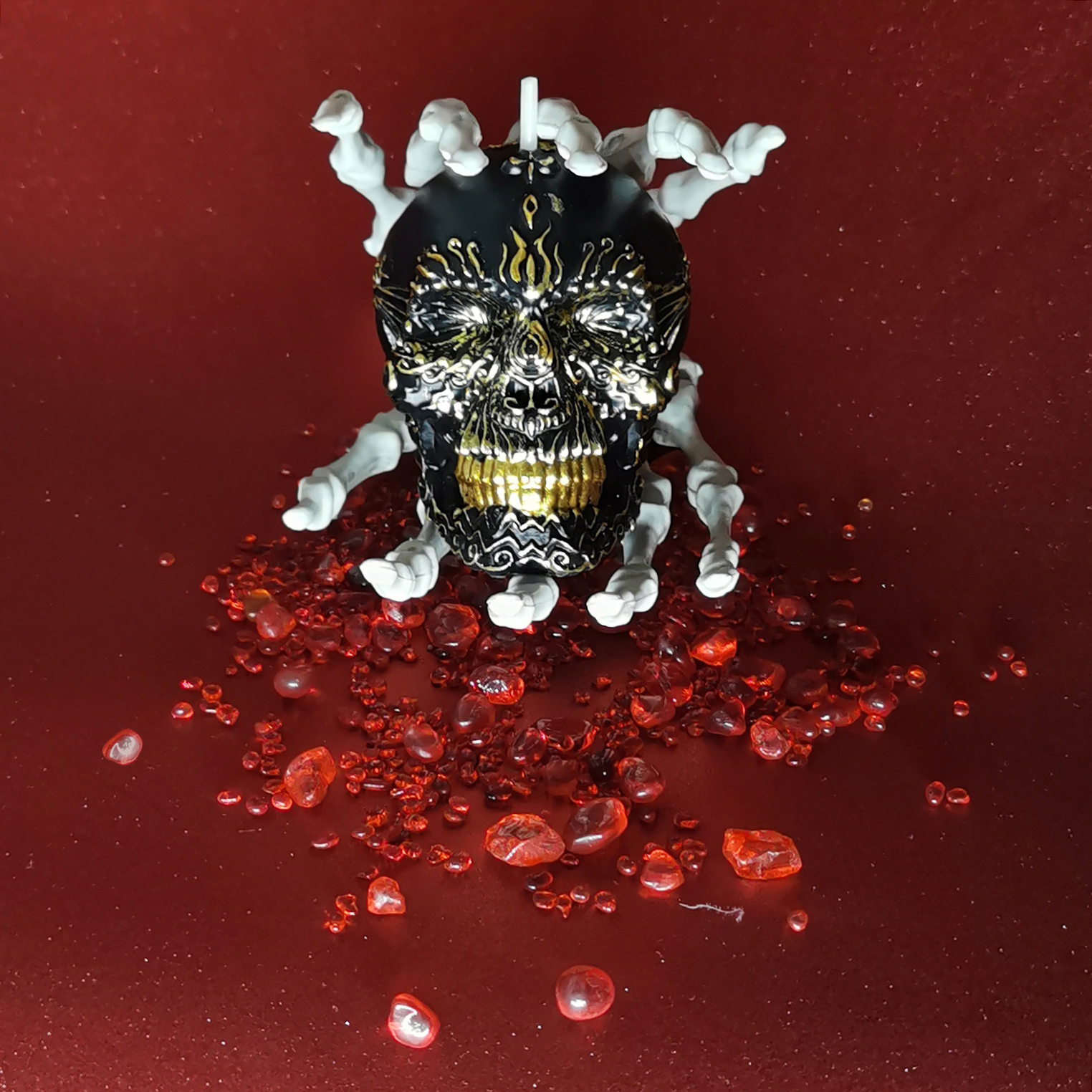 Gilded Black Skull Candle between two skeleton hands_frontview