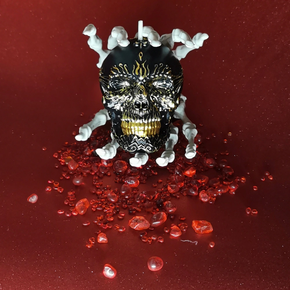 Gilded Black Skull Candle between two skeleton hands_frontview