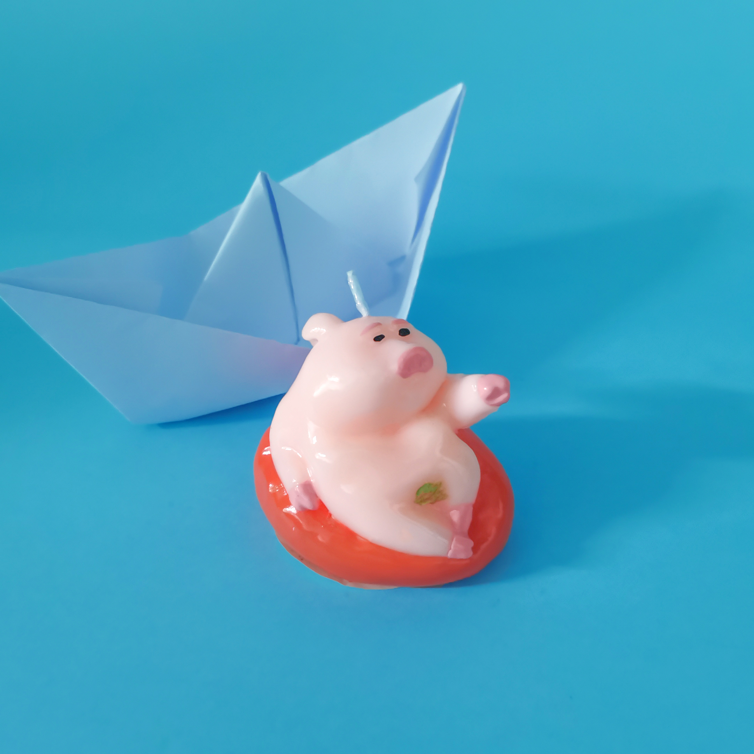 Pink Piggy Candle on the water by a paper boat