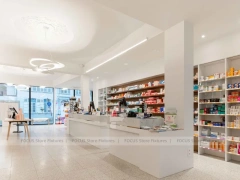 White Pharmacy Reception Counter with Dark Wall Shelves