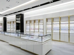 Glossy White Eyewear Boutique Interior with Gold Accent Counter