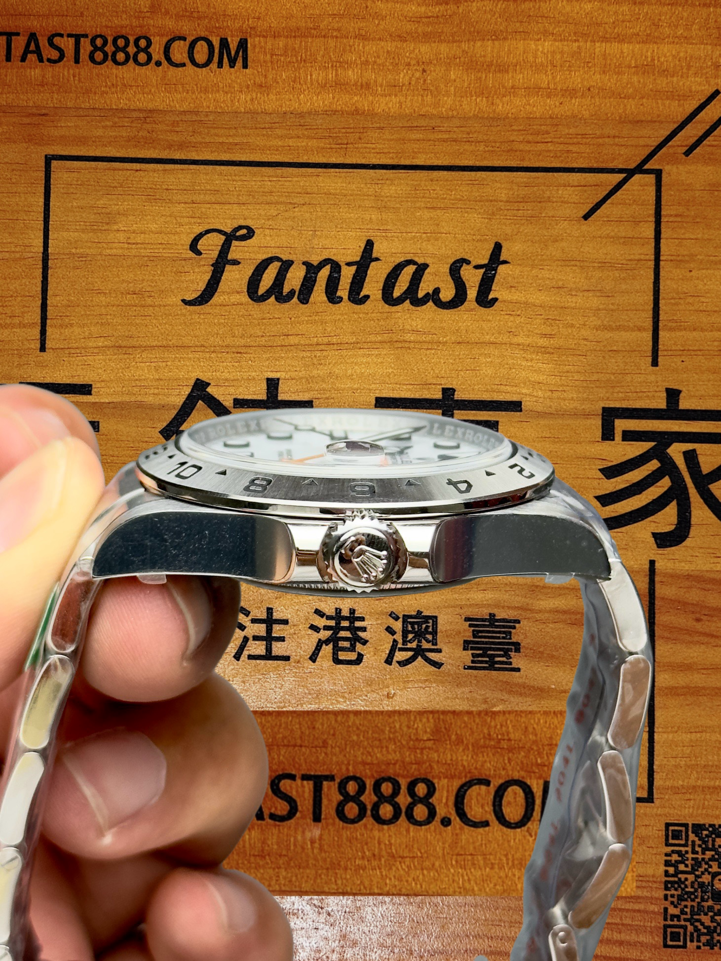 勞力士腕錶側面特寫，展示錶冠皇冠標誌與白色錶盤，佩戴黑色手套手持，背景木紋印有Fantast標誌及「注港澳臺」文字。