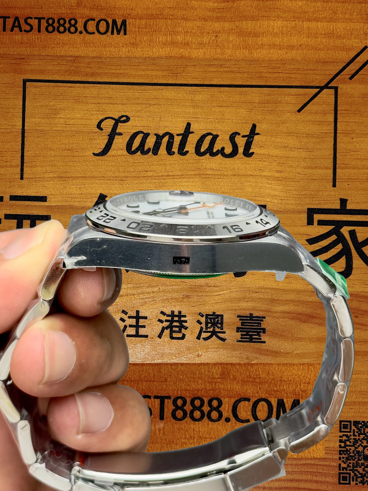 勞力士腕錶側上方視角，清晰顯示錶殼側面Swiss Made印記與白色錶盤數字時標，背景木質板印有TAST888.COM與Fantast字樣。
