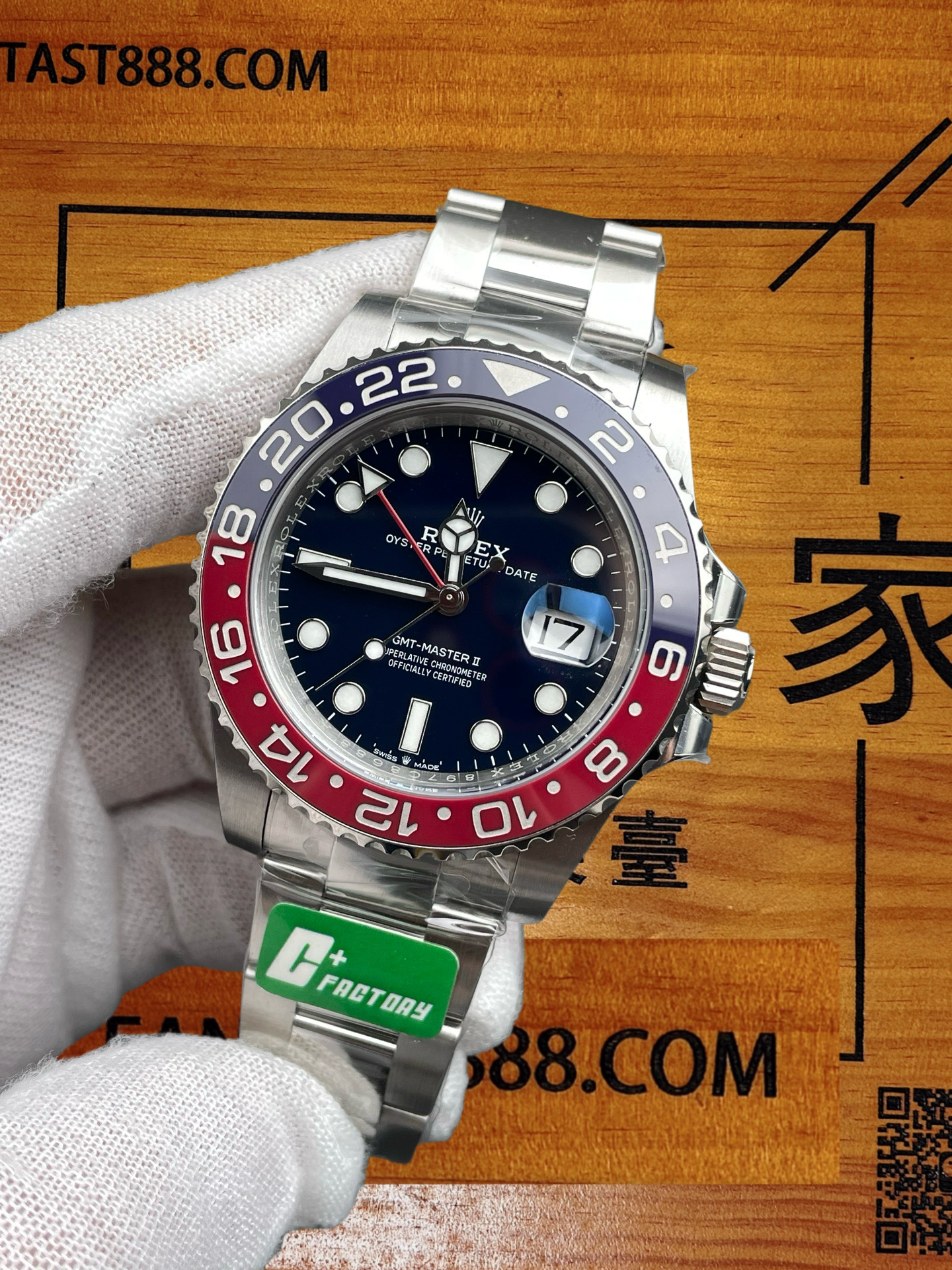 C+廠勞力士格林尼治型II可樂圈復刻腕錶特寫，展示深藍色錶盤、紅藍雙色陶瓷圈與日期顯示，佩戴白手套置於印有FANTAST888.COM字樣的木質背景上。