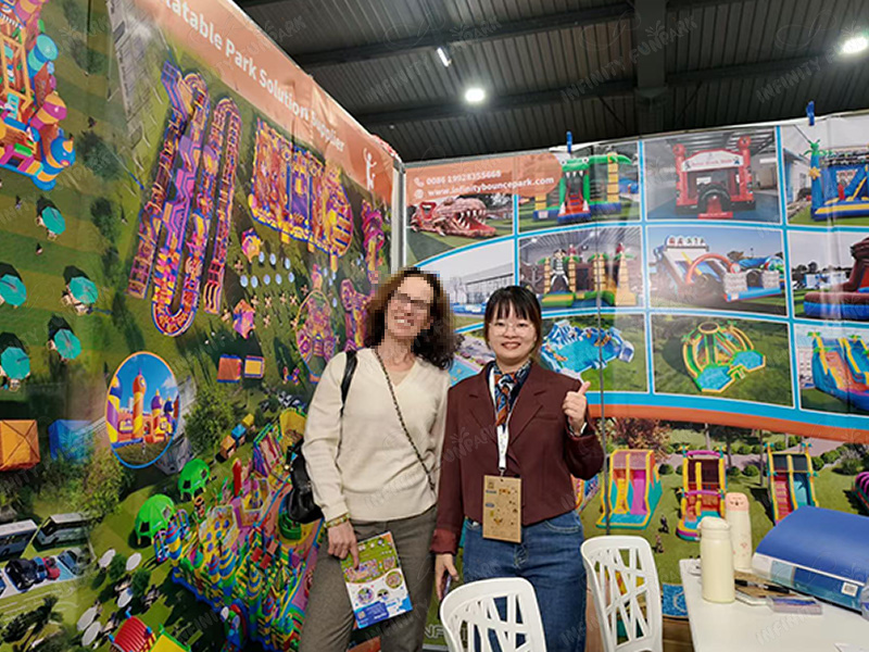 Business professionals reviewing inflatable park project materials at Infinity Funpark booth