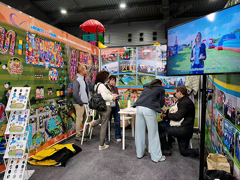 Busy Infinity Funpark booth with multiple international visitors and interactive displays