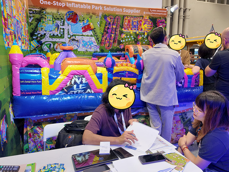 Contract signing and business discussions at Infinity Funpark booth IAAPA 2025