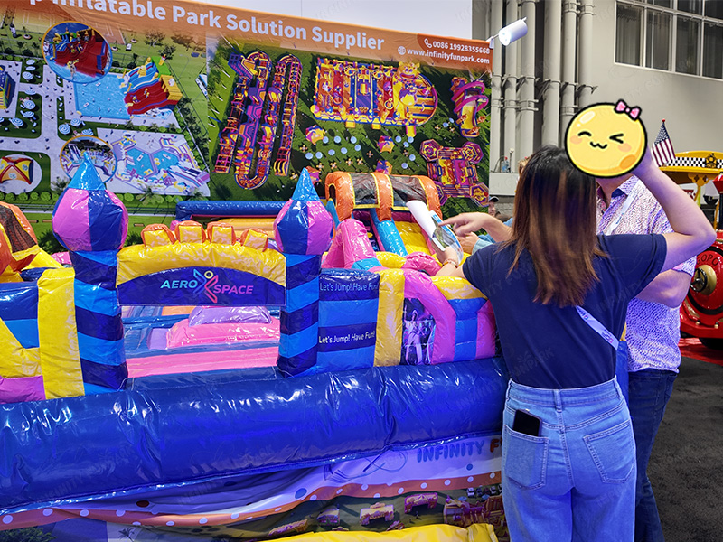 Infinity Funpark team demonstrating inflatable theme park products at IAAPA