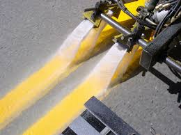 Workers applying AASHTO M247 II reflective glass beads during thermoplastic road marking paint installation, ensuring optimal reflectivity.