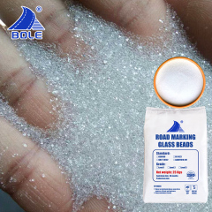 Close-up of AASHTO M247 II reflective glass beads in hand, highlighting their smooth texture and consistent size for optimal reflectivity in road marking applications.