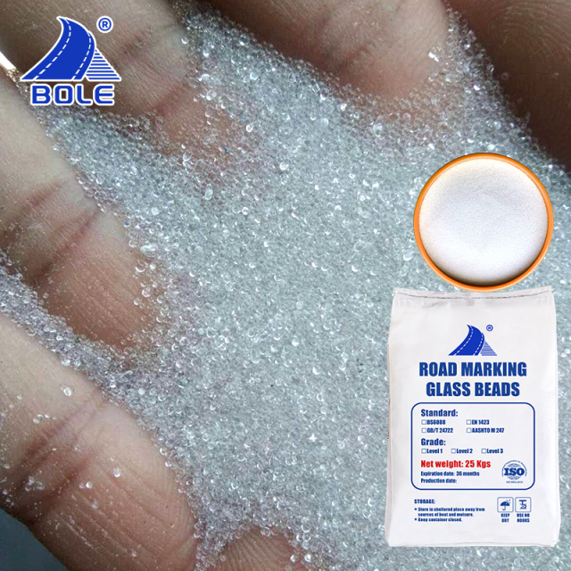 Close-up of AASHTO M247 II reflective glass beads in hand, highlighting their smooth texture and consistent size for optimal reflectivity in road marking applications.