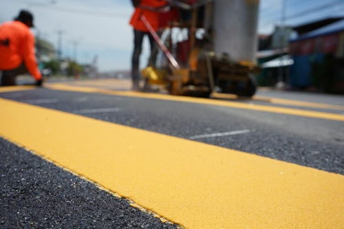 Thermoplastic road marking application showing reflective visibility at night.