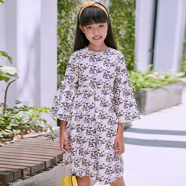 New girls' geometric printed dress: a white base with colorful patterns resembling bows, paired with lively flared sleeves, fully embodying the fashionable and childlike style.