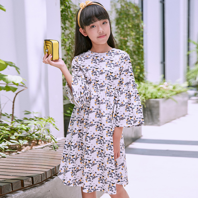 New girls' geometric printed dress: a white base with colorful patterns resembling bows, paired with lively flared sleeves, fully embodying the fashionable and childlike style.