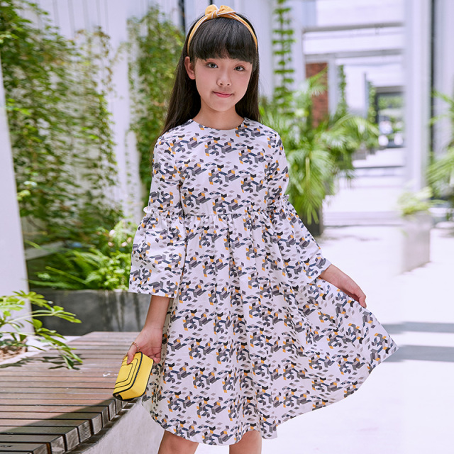 New girls' geometric printed dress: a white base with colorful patterns resembling bows, paired with lively flared sleeves, fully embodying the fashionable and childlike style.