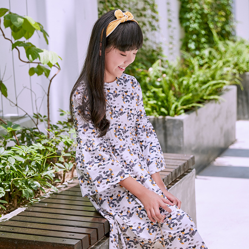 New girls' geometric printed dress: a white base with colorful patterns resembling bows, paired with lively flared sleeves, fully embodying the fashionable and childlike style.