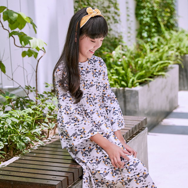 New girls' geometric printed dress: a white base with colorful patterns resembling bows, paired with lively flared sleeves, fully embodying the fashionable and childlike style.
