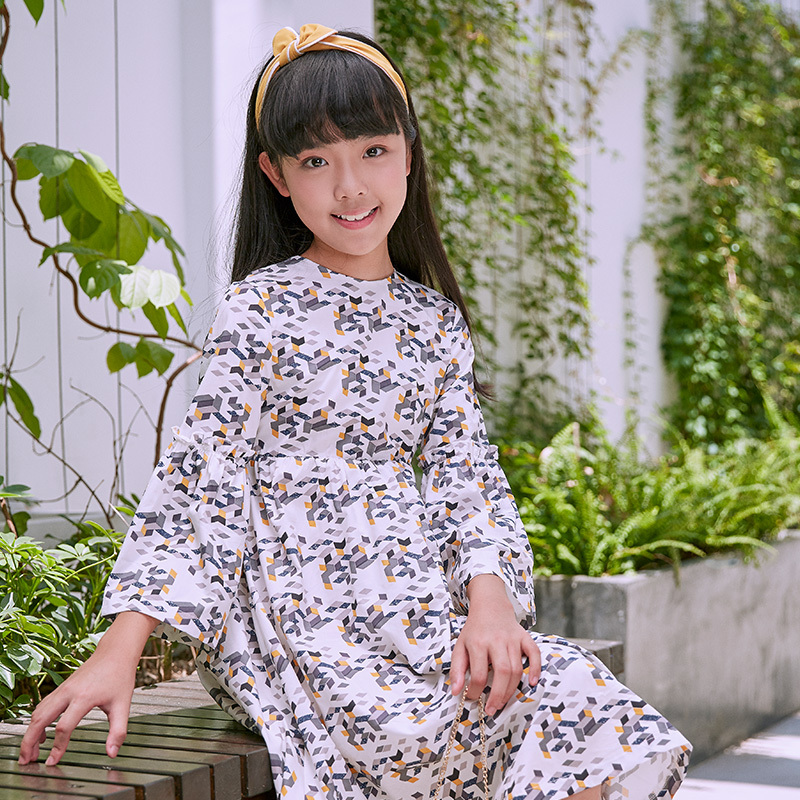New girls' geometric printed dress: a white base with colorful patterns resembling bows, paired with lively flared sleeves, fully embodying the fashionable and childlike style.
