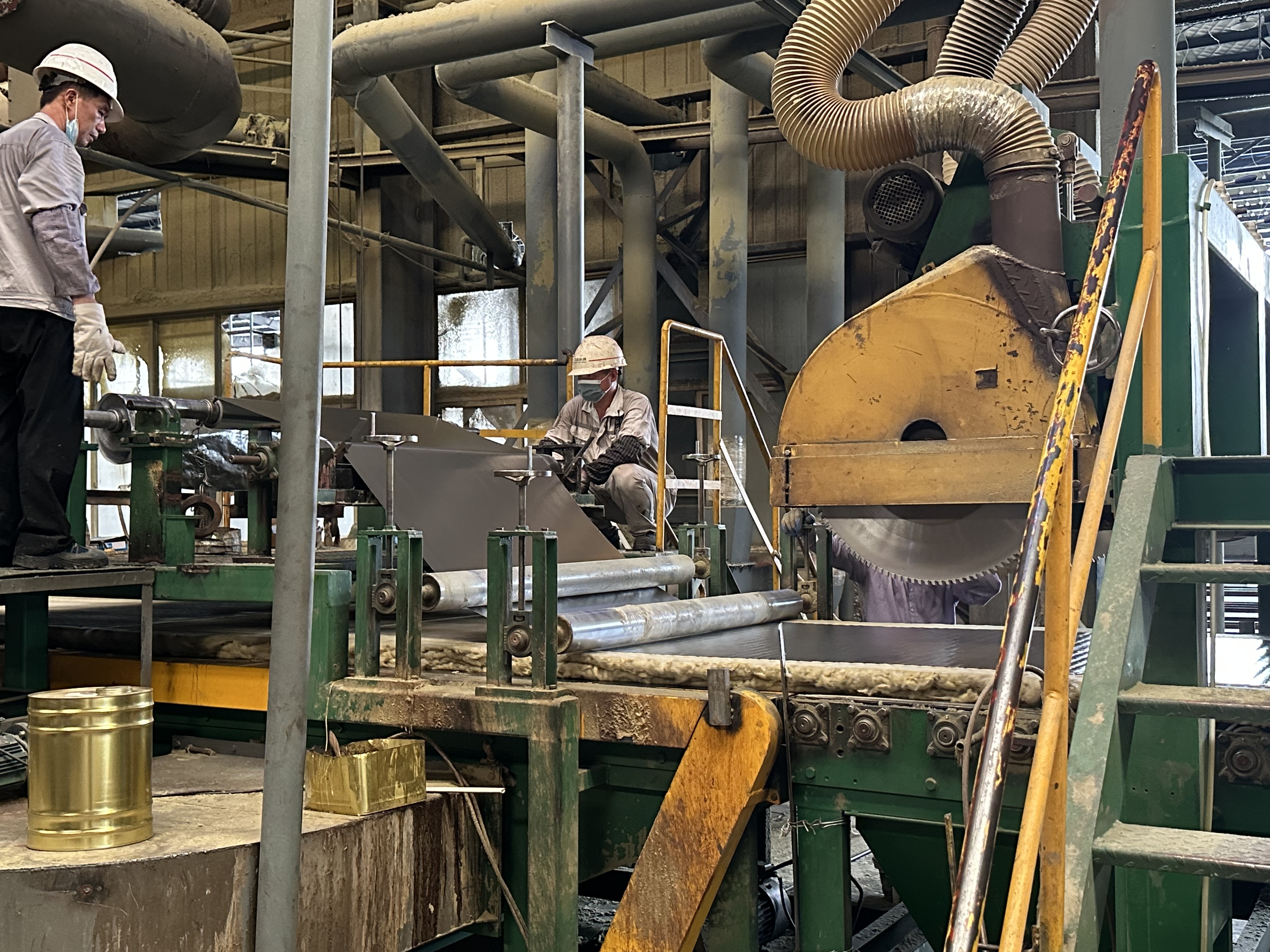 Worker operating aluminum foil lamination machine on production line for foil faced rock wool board - real-time manufacturing process of HVAC insulation by Liluan Technology