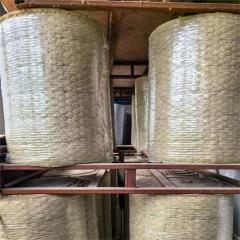 Bare rock wool blanket rolls neatly stored on industrial warehouse racks - high-temperature insulation material by Liluan Technology