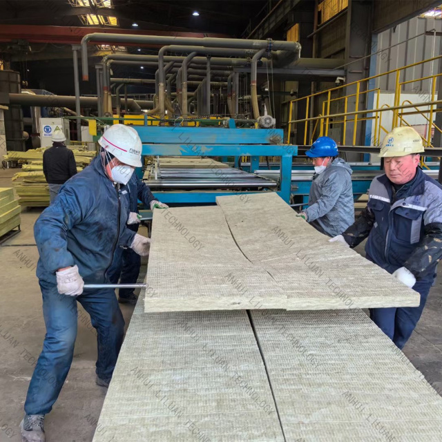 Factory workers carrying large rock wool blanket sheets on the production line at Anhui Liluan Technology factory