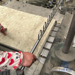 Factory worker operating production line attaching wire mesh to rock wool blanket roll - reinforced insulation manufacturing process at Liluan Technology