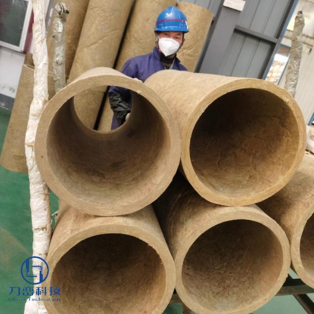 Factory worker holding large rock wool pipe insulation sections - real manufacturing process for industrial heat resistant pipe insulation by Liluan Technology