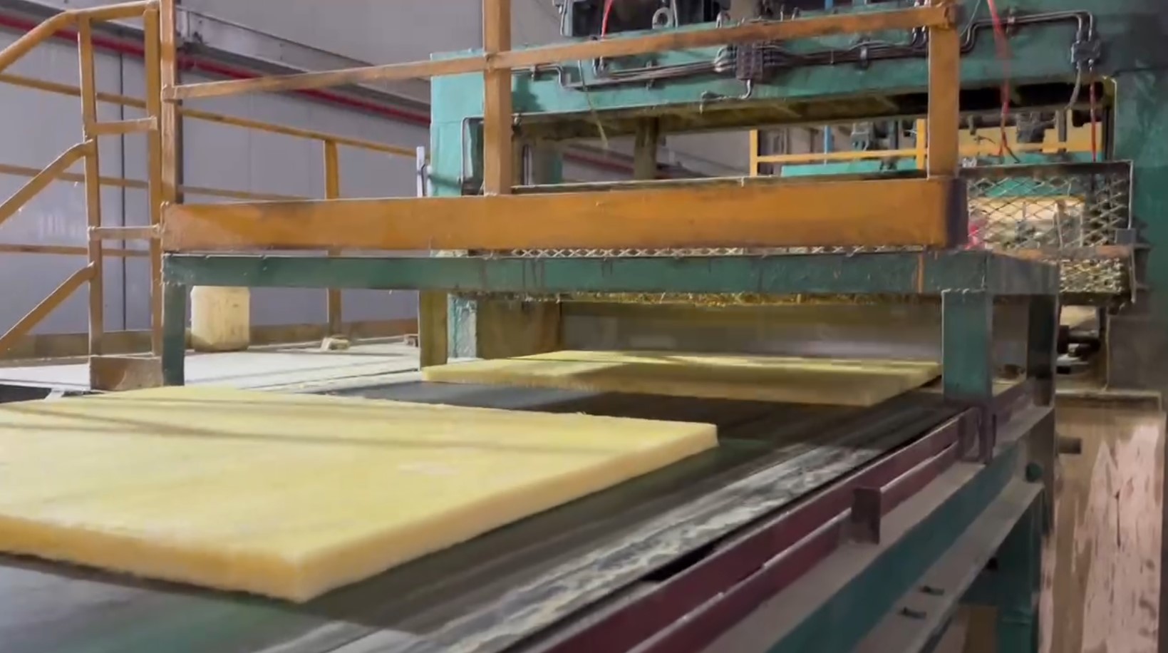 Glass wool board being transported on conveyor belt during manufacturing – lightweight thermal & acoustic insulation by Liluan Technology