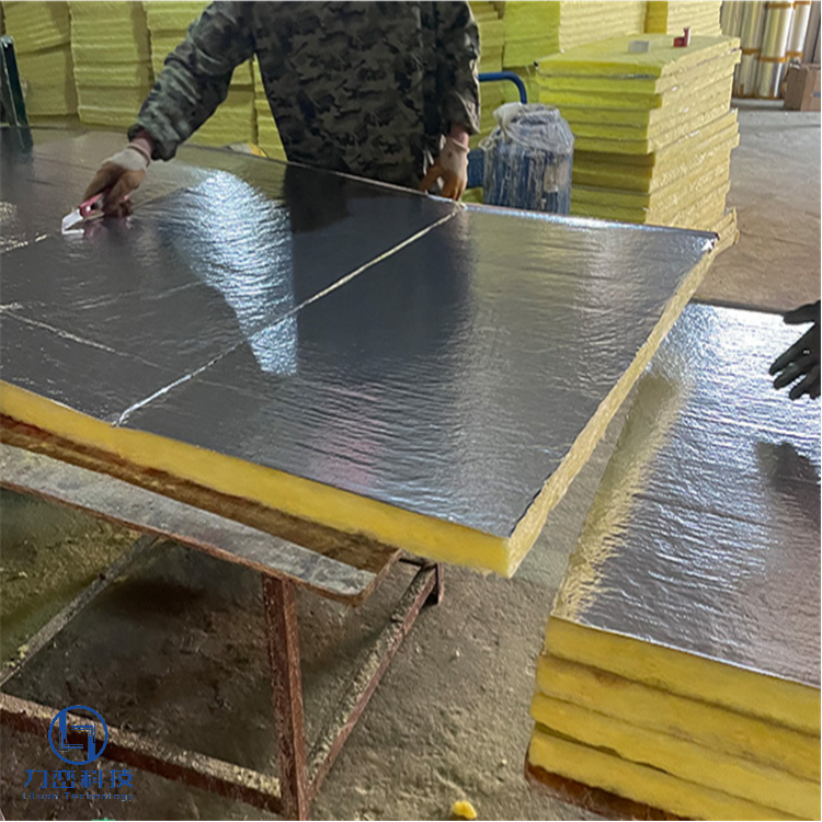 Worker applying aluminum foil facing to glass wool board – manufacturing lightweight thermal & acoustic insulation by Liluan Technology