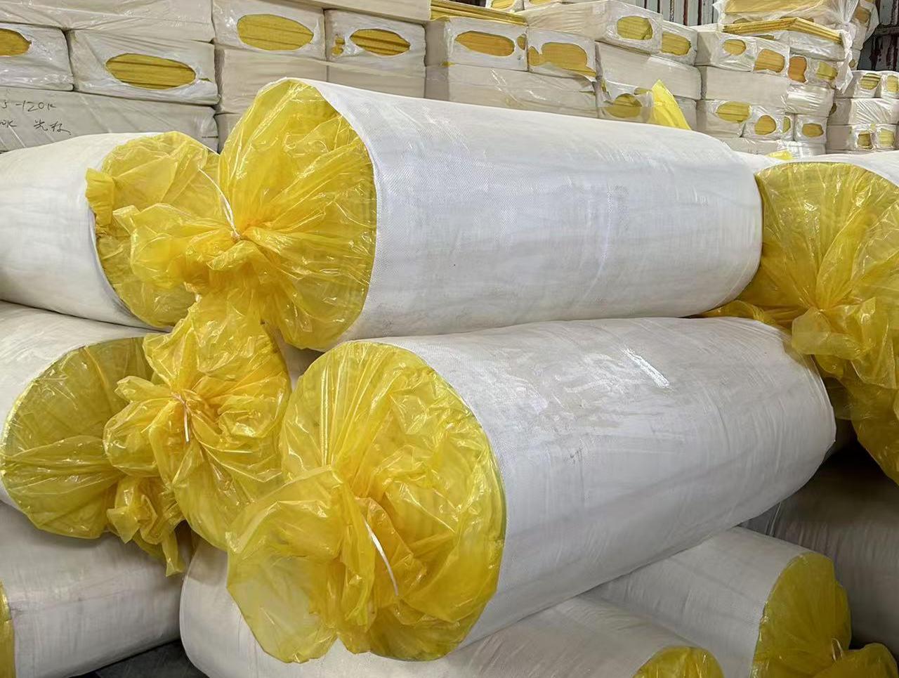 Large stacks of packaged glass wool blanket rolls in warehouse &ndash; flexible thermal and acoustic insulation ready for delivery by Liluan Technology