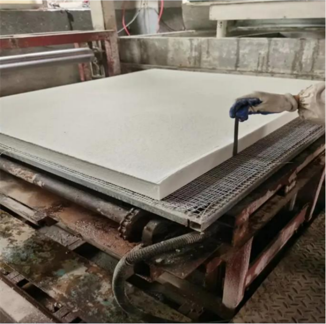Worker handling large aluminum silicate board on production line – manufacturing high-temperature insulation panels by Liluan Technology