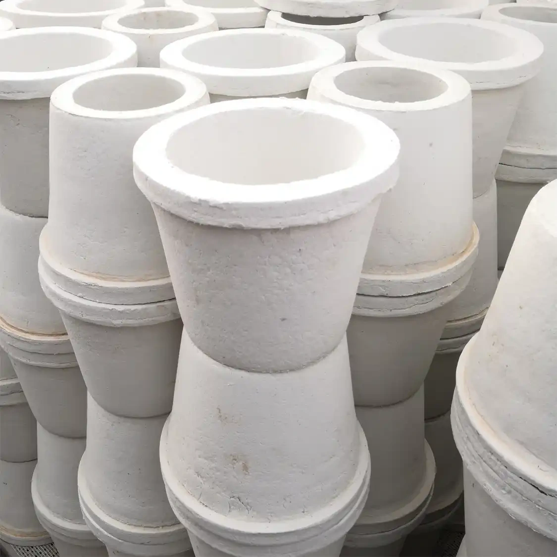 Stacks of identical conical ceramic fiber special-shaped parts, likely used as crucibles or flow distributors, neatly stacked together in a warehouse for bulk supply——LiLuan Technology