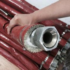 Industrial application of Liluan red fire sleeve protecting a bundle of hydraulic hoses and metal fittings in high-heat metallurgy environments.---LiLuan Technology
