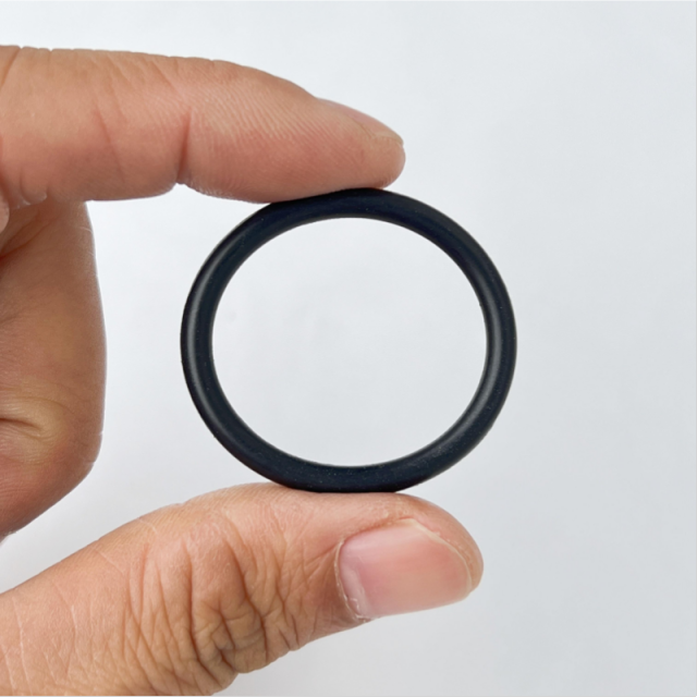Single black FKM (Viton) O-ring seal held in fingers, industrial rubber O-ring gasket with excellent chemical resistance and low compression set-LiLuan Technology