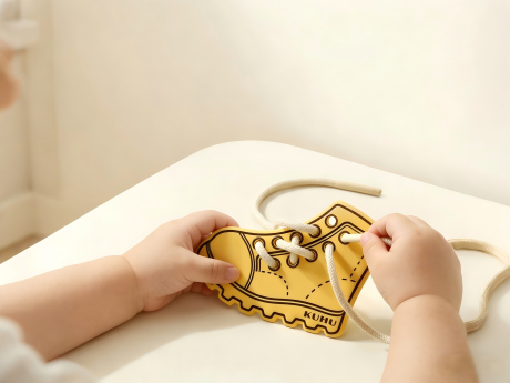 toddler practicing threading and tying fine motor skills with a lace toy