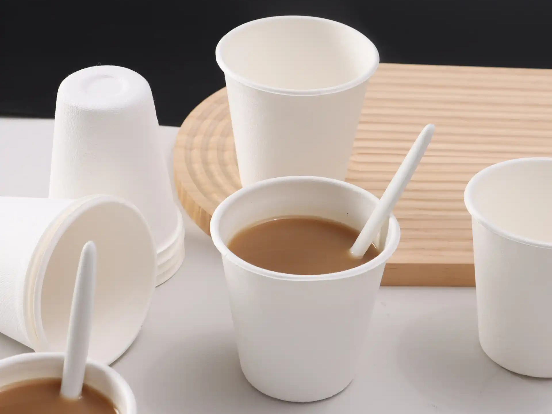White cups arranged with spoons and a wooden tray, including a cup holding a brown beverage