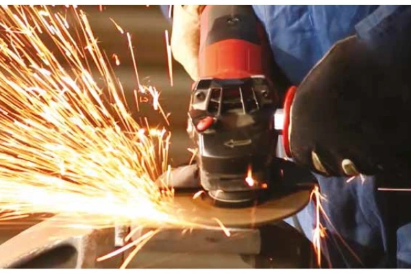 A close-up action shot of a FUJI JITAN Grinding Wheel smoothly grinding a steel workpiece