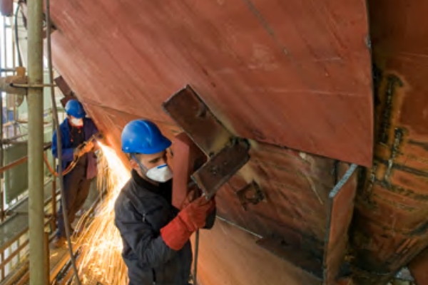 Worker using Fuji 115mm grinding wheel on ship hull